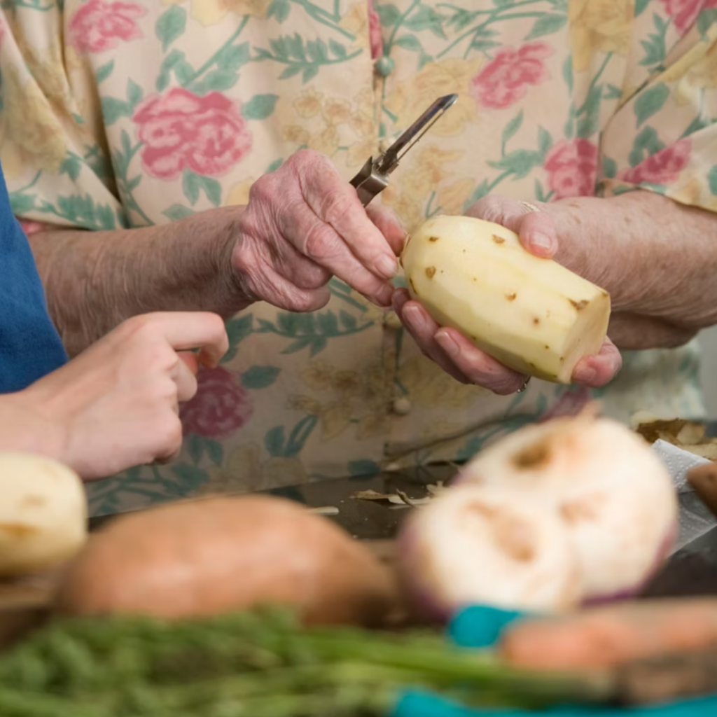 Photo of an elderly woman's hands as she prepares food with a younger child