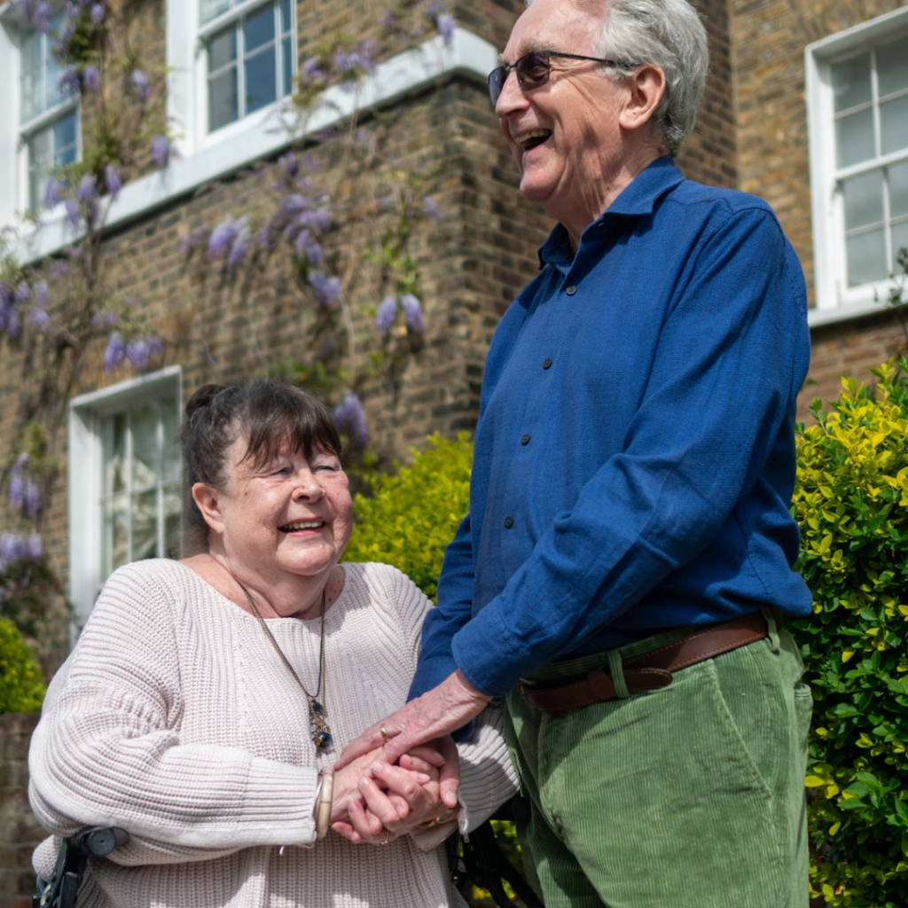 Man and woman holding hands and smiling outdoors on a sunny day